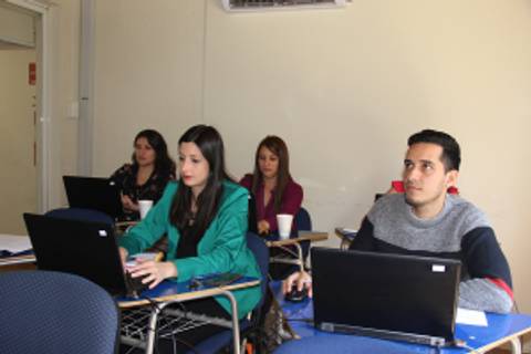 Un grupo de cuatro personas sentadas en un aula, utilizando computadoras portátiles.