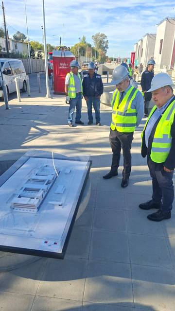 Un grupo de personas en el lugar de construcción observa un modelo arquitectónico.