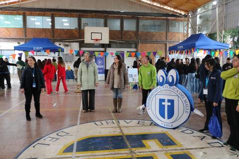 Una actividad universitaria en el gimnasio con estudiantes y stands informativos.