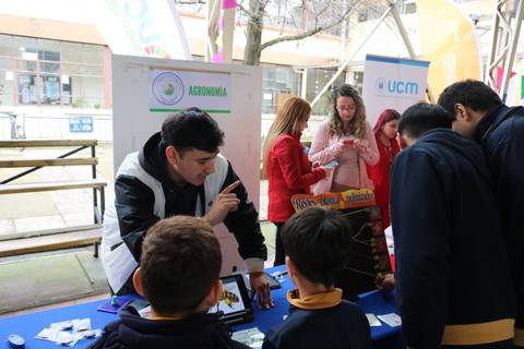 Un grupo de estudiantes interactúa con un expositor en una feria de agronomía.