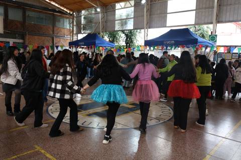 Un grupo de personas bailando en una celebración con vestimenta colorida en un gimnasio.