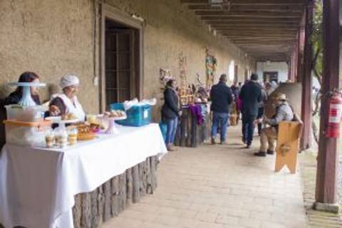 Una escena de un mercado al aire libre con vendedores y compradores en un pasillo.