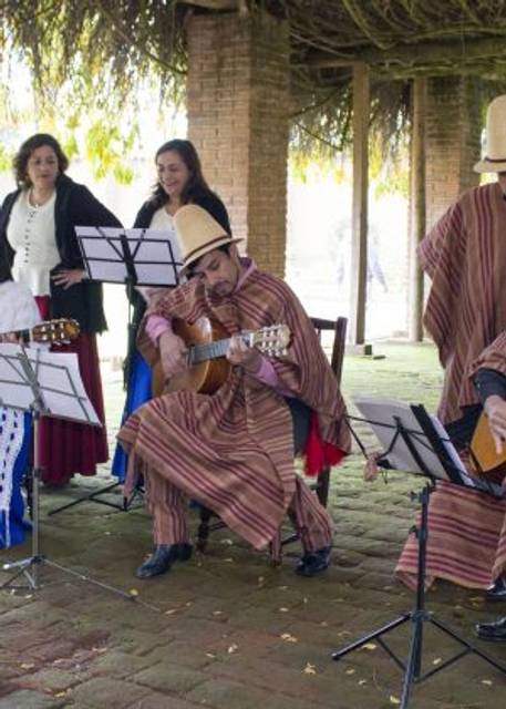 Un grupo de músicos interpretando música tradicional con guitarras en un ambiente al aire libre.