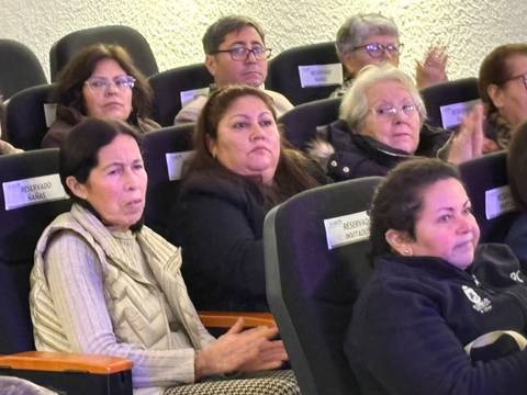 Un grupo de personas mayores asistiendo a un evento en una sala.