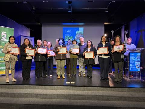 Un grupo de personas sonrientes sosteniendo certificados en un evento de entrega de distinciones.