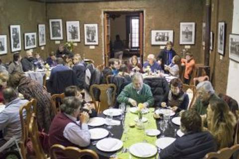 Una multitud de personas disfruta de una comida en un comedor familiar con fotos en las paredes.