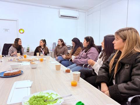 Un grupo de mujeres conversando y compartiendo en una reunión en una sala.