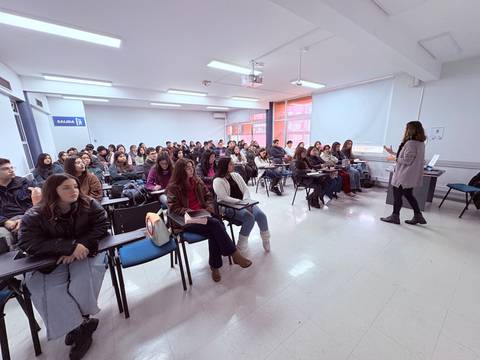 Una profesora está dando una charla a un gran grupo de estudiantes en un aula.