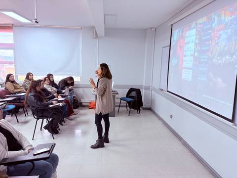 Una persona expone frente a un grupo de alumnos en un aula.