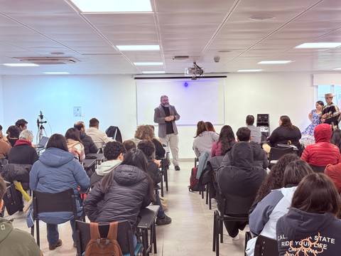 Una charla con un expositor frente a un grupo de estudiantes en un aula.