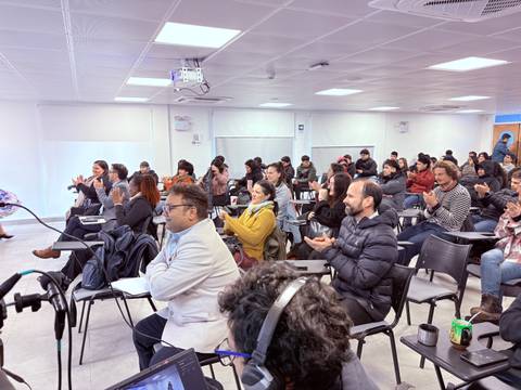 Un grupo de personas aplaudiendo en un evento o charla en una sala.