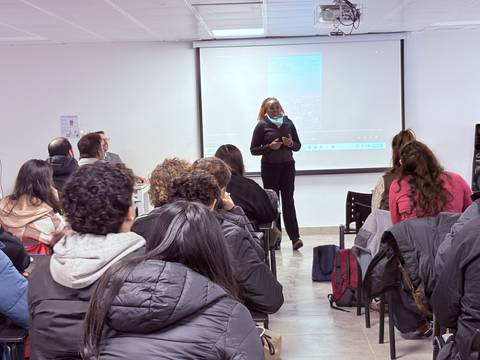 Una charla en un aula donde una persona está presentando frente a un grupo de asistentes.