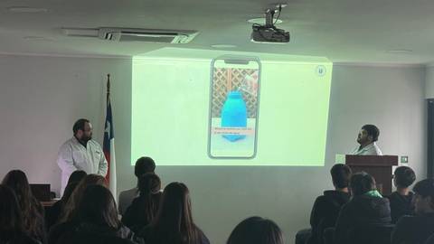 Presentación sobre un dispositivo en un aula con estudiantes atentos.