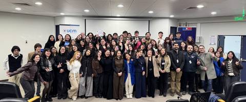 Una gran cantidad de personas posan juntas en una sala para una foto grupal en un ambiente académico.