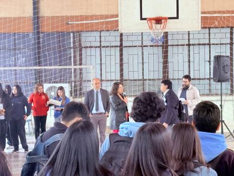 Una actividad escolar en un gimnasio donde se están entregando premios y hay varios estudiantes presentes.