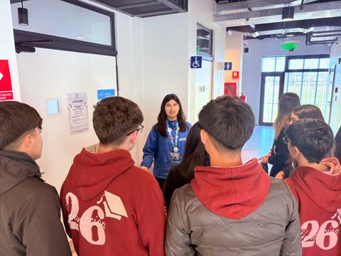 Un grupo de estudiantes escucha atentamente a una guía que les explica algo importante.