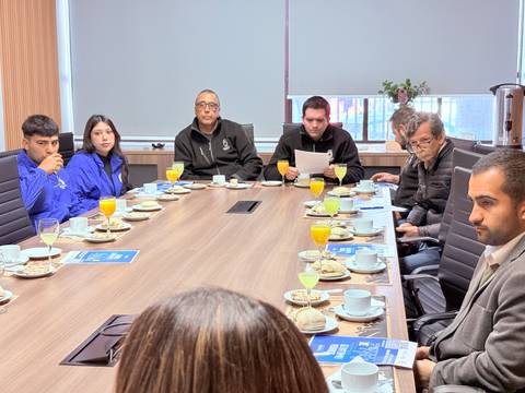 Una reunión en una sala con asistentes sentados alrededor de una mesa con bebidas y aperitivos.