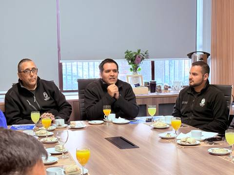 Un grupo de hombres conversando en una reunión con bebidas y bocadillos en la mesa.