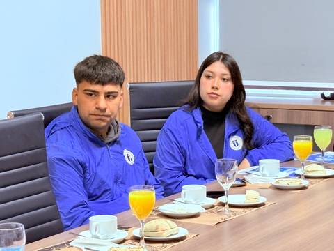 Dos jóvenes sentados en una mesa durante un desayuno formal.
