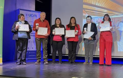 Un grupo de personas sostiene certificados en un evento de reconocimiento.