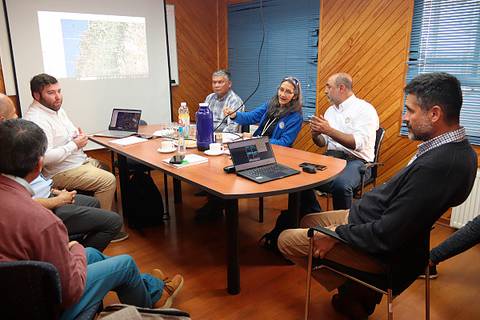 Una reunión de trabajo en una sala con varias personas discutindo proyectos.