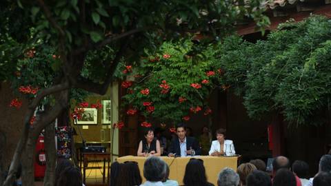 Un grupo de personas participa en una charla al aire libre en un ambiente rodeado de naturaleza.