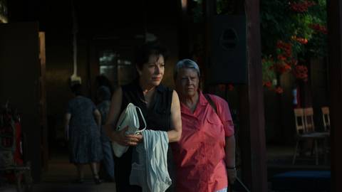 Dos mujeres conversan en un entorno al aire libre, rodeadas de un ambiente cálido y natural.