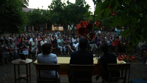 Una multitud observa un evento al aire libre en un entorno rodeado de árboles.