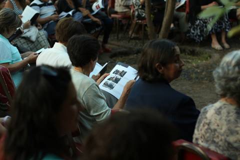 Un grupo de personas sentadas en un evento, sosteniendo folletos con imágenes.