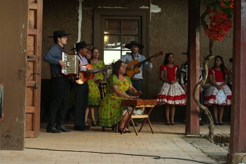 Un grupo de músicos y bailarines en un escenario, vestidos con trajes tradicionales, interpretando música folclórica.