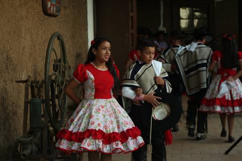 Un grupo de niños vestidos con trajes tradicionales, algunos bailando y otros observando en un ambiente festivo.