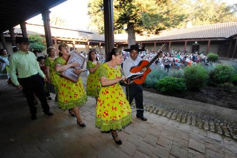 Un grupo de personas vestidas con trajes tradicionales se prepara para una actuación musical en un entorno al aire libre.