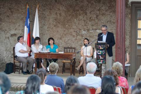 Un grupo de personas está participando en un evento en un ambiente al aire libre, con banderas chilenas al fondo.