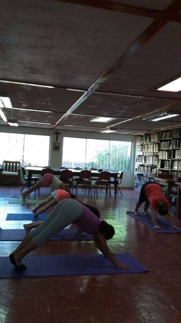 Un grupo de personas practicando yoga en un salón con estanterías de libros.