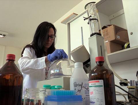 Una científica trabajando en un laboratorio con frascos y equipos.