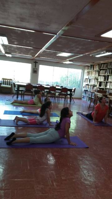 Un grupo de personas realiza una práctica de yoga en un ambiente de biblioteca.