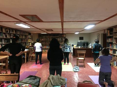 Un grupo de personas practicando yoga en una sala con estanterías de libros.