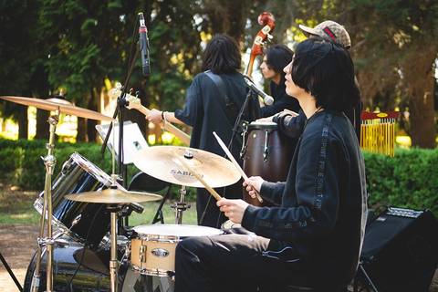 Un grupo de músicos tocando en un parque, con un baterista en primer plano.