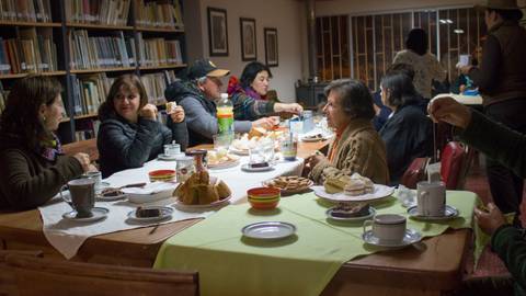Un grupo de personas conversando y compartiendo alimentos en un ambiente acogedor de biblioteca.