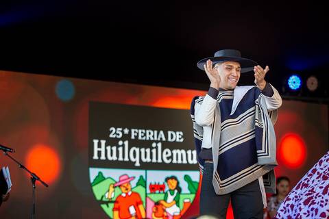 Un hombre vestido con traje tradicional celebra en un escenario durante la Feria de Huilquilemu.