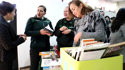 Un grupo de mujeres conversando y revisando libros en un evento.