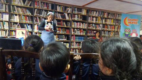 Una narradora cuenta cuentos a un grupo de niños en una biblioteca.