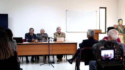 Un grupo de personas discutiendo en una mesa durante un evento en una sala de conferencias.
