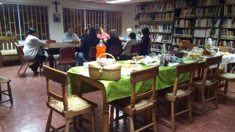 Un grupo de personas se reúne en una sala con mesas y estanterías llenas de libros.