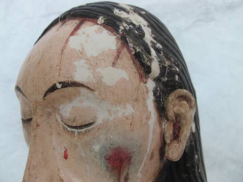 Retrato en primer plano de una figura artística con detalles desgastados y pintura deteriorada.