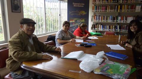 Un grupo de cuatro personas sentadas alrededor de una mesa en un entorno de biblioteca.
