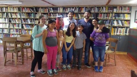 Un grupo de niños y adultos sonríen juntos en una biblioteca.