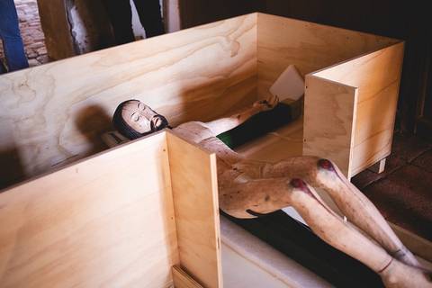 Una figura de madera que parece un maniquí yace dentro de una caja de madera sencilla.