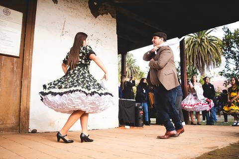 Una pareja baila en un ambiente festivo con un vestido tradicional y una actitud alegre.