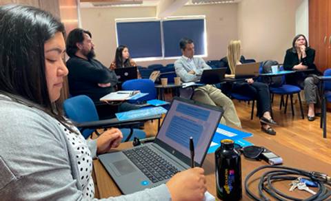 Un grupo de personas en una reunión con laptops, prestando atención a una presentación.